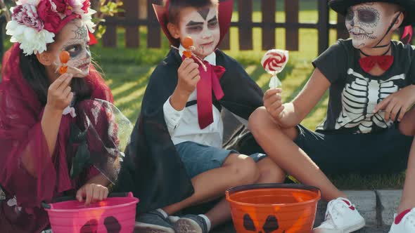 Cheerful Kids in Halloween Costumes Sharing Candy alt