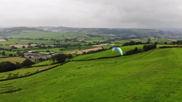 Aerial shot of a Paraglider coming into land with the English countryside behind alt