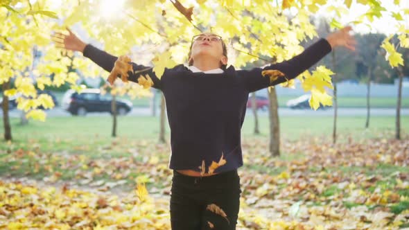 Girl Throws Up Leaves and Having Fun in Autumn Park