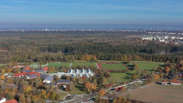 Autumn landscape of a village with playgrounds for soccer and the skyline of the bavarian city Munic alt