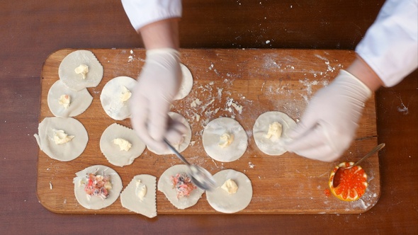 Putting seafood filling on a dough, preparing homemade dumplings
