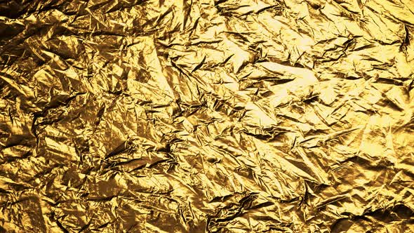 Crumpled, golden foil shining in the spotlight. Endless, abstract pattern. 4K HD