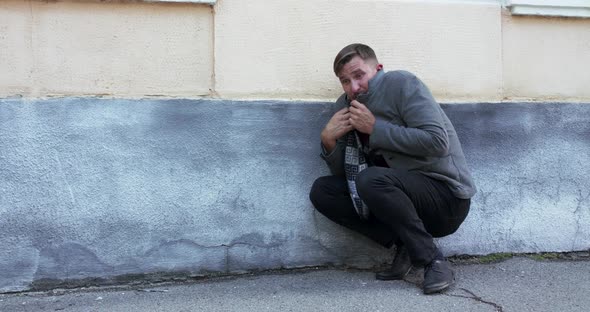 The Man Wraps Around with Scarf and Jacket Hits Numb Body at Street Building alt