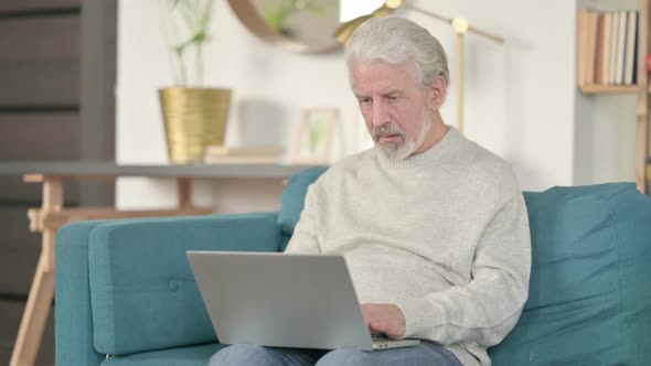Old Man with Laptop Reacting to Failure on Sofa alt