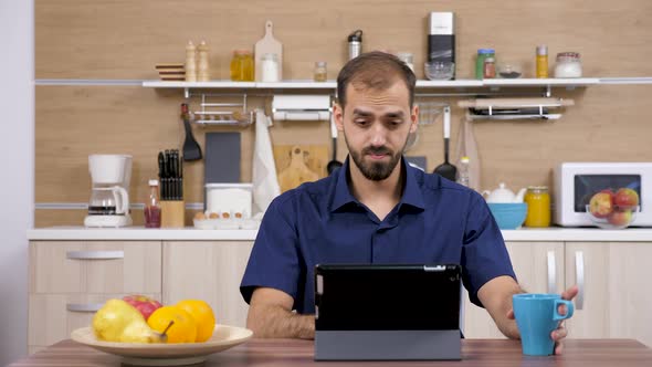 Man in the Kitchen Looking at Digital Tablet PC alt