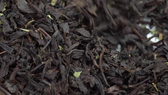 Spoon Picks Up Dried Black Tea Leaves Leafy Black Tea on a Plate alt