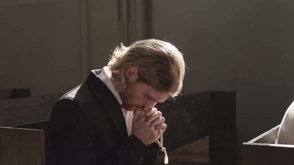 Young Caucasian Man Praying in Christian Church alt