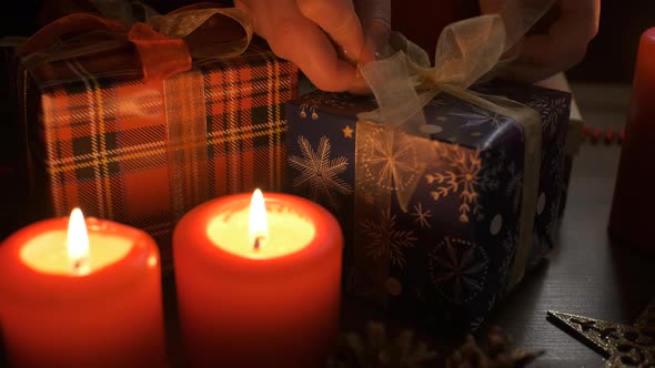 Female Hands Put and Finalize Christmas Gift on a Table Decorated alt