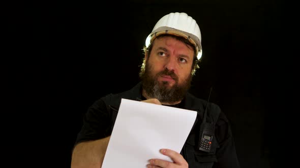 Skeptical bearded inspector with helmet is unsettled and worried about something