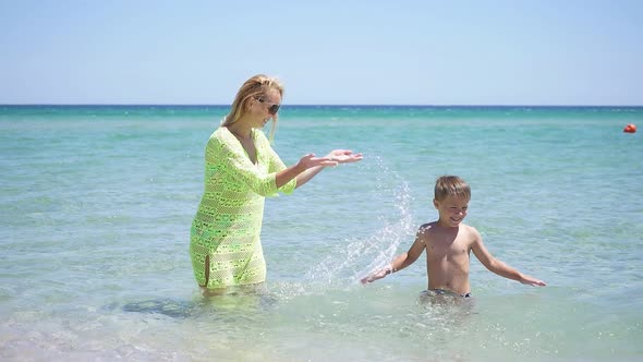 Mom and Son Have Fun Playing in the Sea Making Splashes of Water