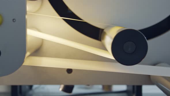 Closeup on paper moving through a large industrial printing machine alt