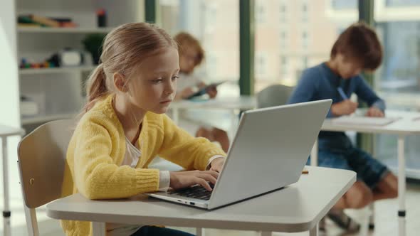 Side View of the Girl Student Using Laptop for Studying Purposes at School in the Class and Other alt