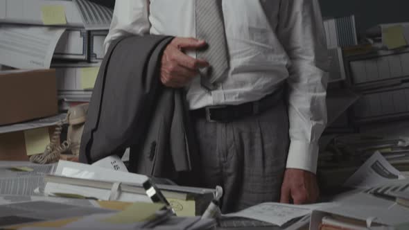 Stressed businessman surrounded by piles of paperwork