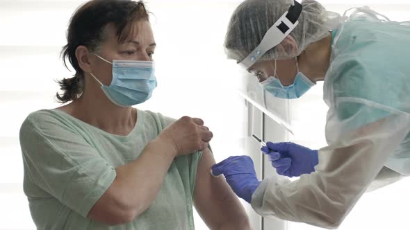 Doctor or Nurse Injects the COVID19 Vaccine Into an Elderly Female Patient's Shoulder alt