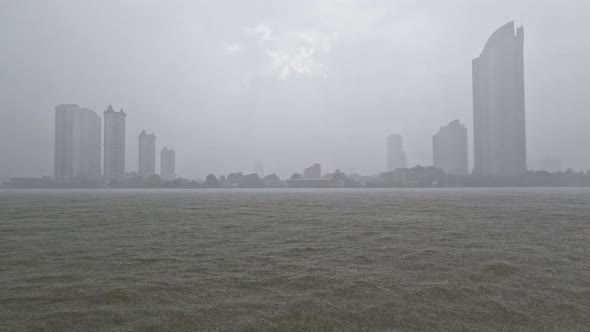 Heavy rain or rainstorm over Chao Phraya River in Bangkok with high buildings silhouette in backgrou alt