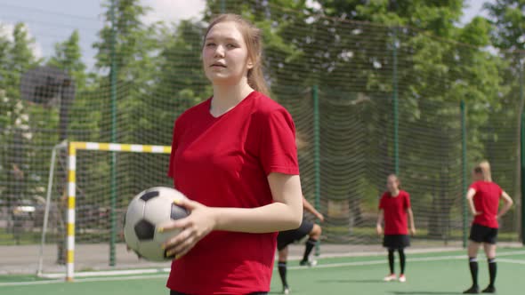 Young Female Athlete Juggling Soccer Ball and Posing for Camera alt