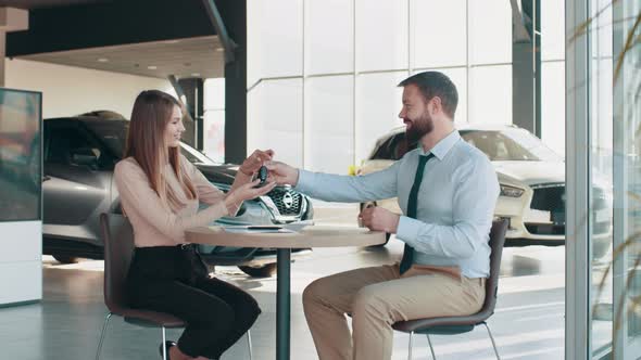 European Female Client Signing Papers with Salesman in Dealership Store alt