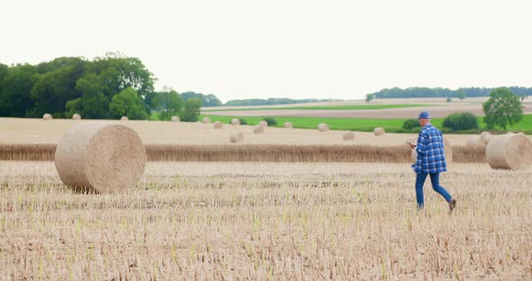 Farmer Using Digital Tablet While Examining Field alt