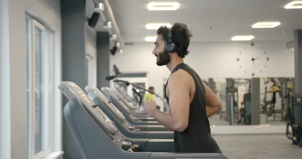 Young Darkhaired Athlete on a Treadmill in a Modern Gym alt