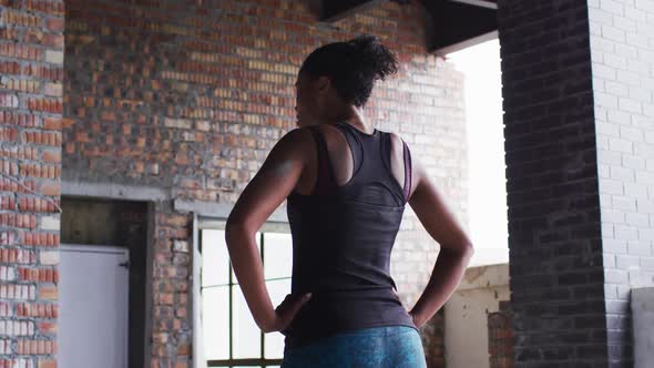 African american woman standing and resting after exercise in an empty urban building alt