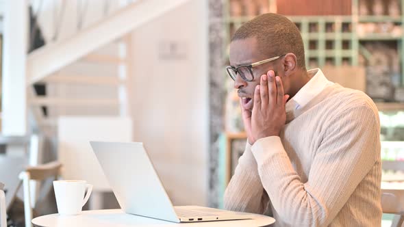 Loss, African Man Reacting To Failure on Laptop in Cafe alt