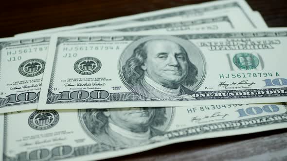 Hundred Dollar Bills Fall on Brown Table