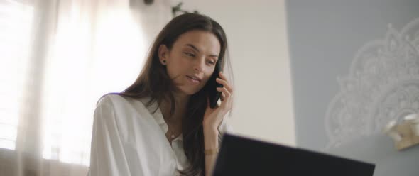 Close up of a woman in white shirt talking to someone on the phone,  alt