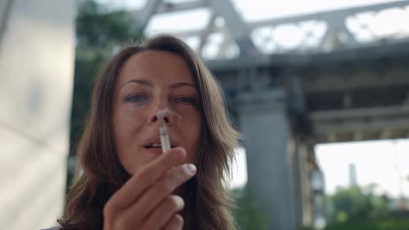 a Female Portrait Against the Background of a Railway Bridge with Passing Vehicles is Out of Focus alt