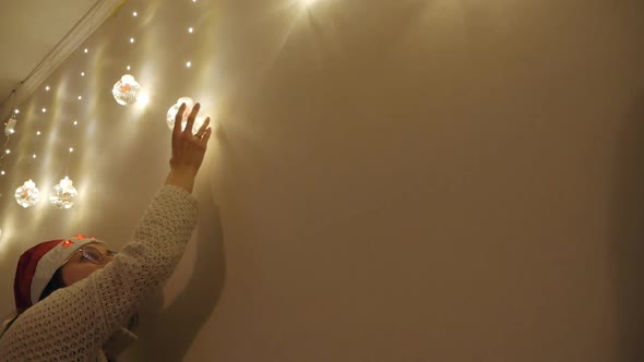 A Christmas Decoration Hangs on the Wall a Woman's Hand Touches It