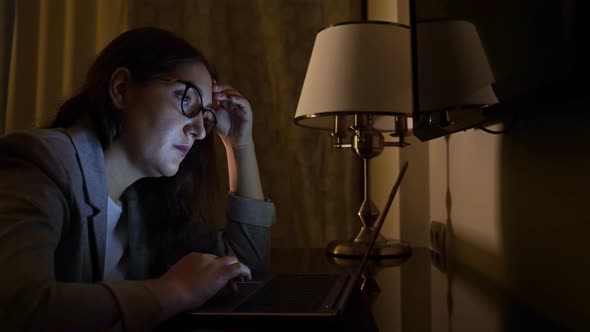 Woman in a Business Suit in a Dark Evening Sits at a Laptop Slow Motion alt