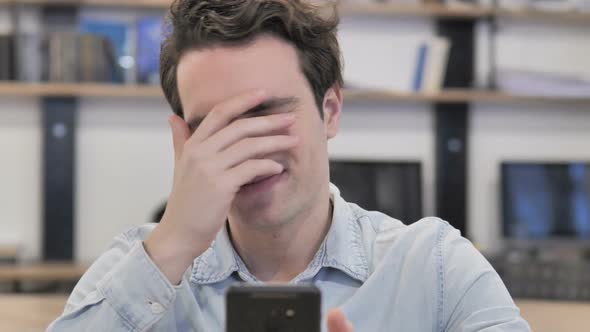 Portrait of Creative Man Reacting to Loss While Using Smartphone alt