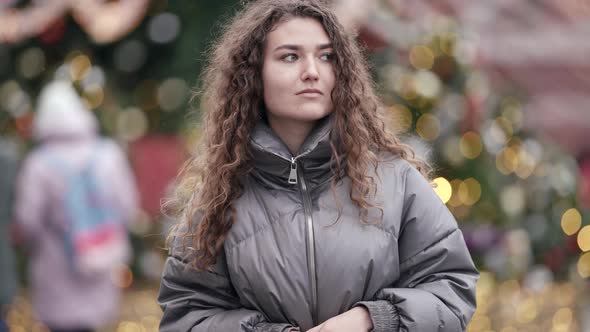 Young Woman Walks Alone at Christmas Holidays on City Street Festive Illumination in Background alt