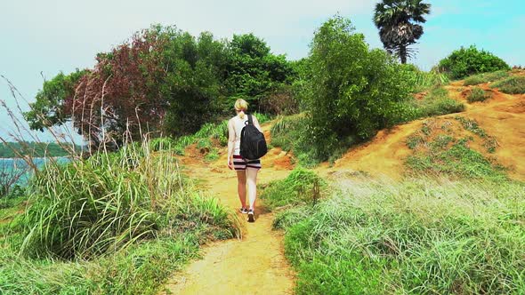 traveler tourist girl walking along a trail on a tropical island to the sea alt