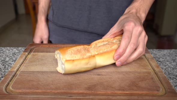 Guy Put And Show Cuban Bread On Wooden Chopping Board. - close up alt