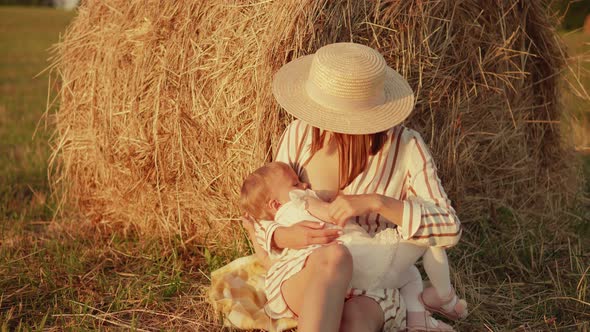 Mother breastfeeds her baby in a field near the village