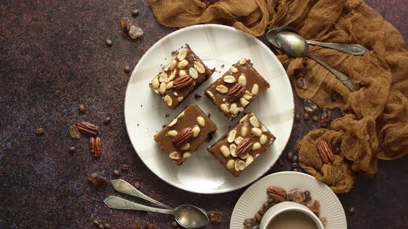 Top View of 4 Square Dark Peanut Brownies with Nuts on a Ceramic Saucer