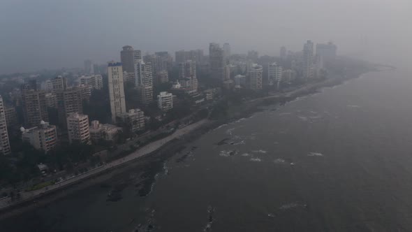 Rotating drone shot of Mumbai coastline on a hazy day high tide alt