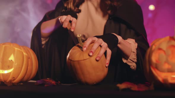 A witch carves a pumpkin for halloween. Beautiful lighting. Halloween! 4K.  Stock video.