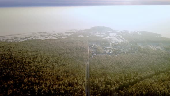 Aerial View of the Winter Forest with Snowcovered Trees with a Village Road with a Smooth Transfer
