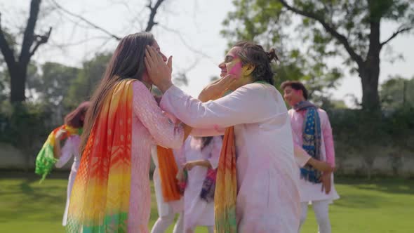 Cute Indian couple put color on each other face on Holi occasion alt