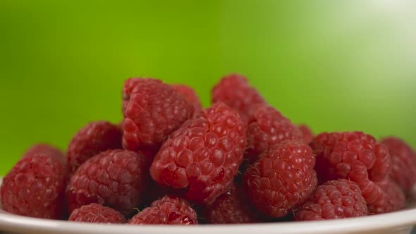 Red Juicy Raspberries Fruit in White Plate on Green Background