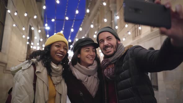 Group of Happy Friends Taking a Selfie with Smartphone in Winter Vacations in the City alt