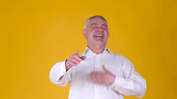 Cheerful elderly man laughing and pointing at you by forefingers.