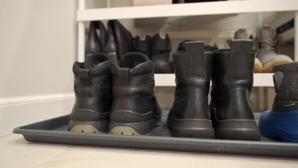 Family Winter Boots Lined Up on Hallway Rug Men Women and Tiny Baby Shoes alt