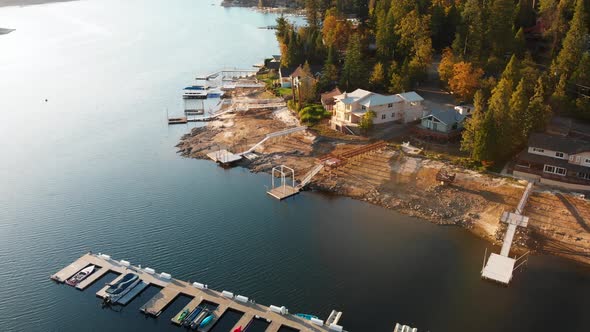 Aerial shot of homes with private docks on a beautiful lake during golden hour. alt