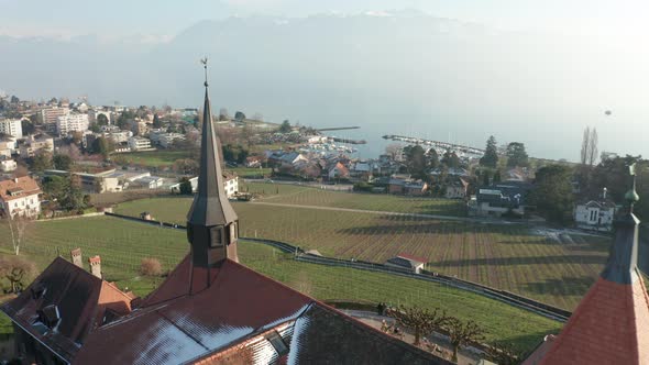 Flying past church tower overlooking green field alt