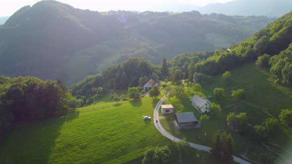 Flying over a small farm atop of a hill in scenic Valley in Slovenia. Idyllic rural landscape in fal alt