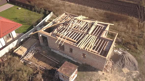 Top down aerial view of two private houses, one under construction with wooden roofing frame  alt