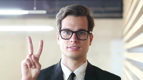 Sign of Victory by Young Businessman in Suit, Portrait alt