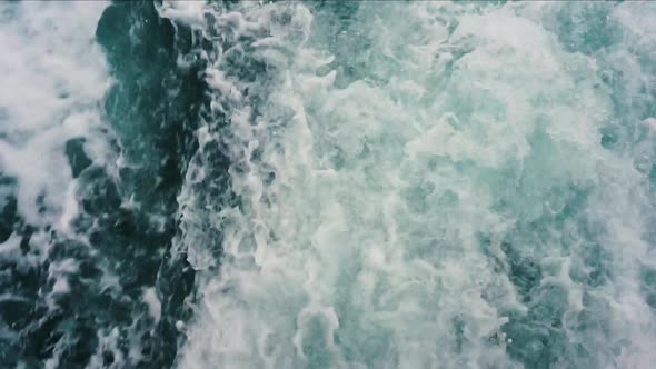 Slow motion froth splashing up behind boat creating blue and white imagery alt